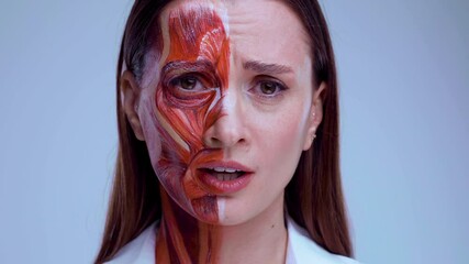 Young woman with half of face with muscles structure under skin. Model for medical training on a light background. Close up video of face human anantomy.