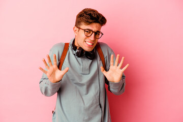 Young student man isolated on pink background rejecting someone showing a gesture of disgust.