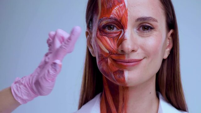 Botox injection in the face. Young woman with half of face with muscles structure under skin. Model for medical training on a light background. Close up video of face human anantomy.