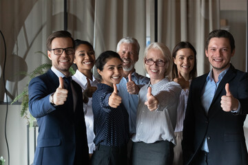 Portrait of smiling diverse multiethnic businesspeople pose in office show thumb up give...