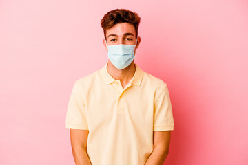 Young caucasian man wearing a protection for coronavirus isolated on pink background funny and friendly sticking out tongue.