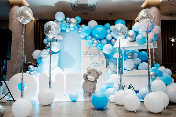 Festive background decoration letters saying one and white blue balloons in studio. Baby birthday theme with teddy bear. Baby Boy. Cake Smash first year concept. birthday greetings. Candy bar.
