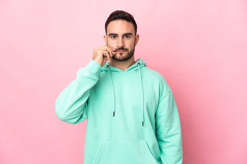 Young caucasian handsome man isolated on pink background showing a sign of silence gesture