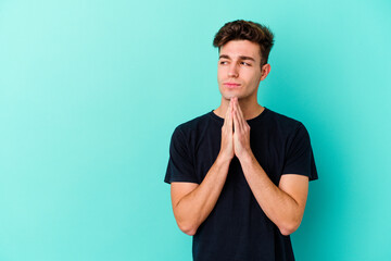 Young caucasian man isolated on blue background making up plan in mind, setting up an idea.