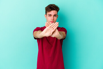 Young caucasian man isolated on blue background doing a denial gesture