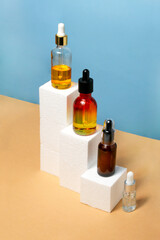 Pipette cosmetics bottles in a row on natural beige and blue background. Set of cube geometric stairs product promo