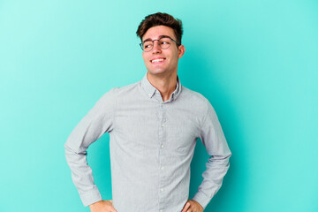 Young caucasian man isolated on blue background laughs happily and has fun keeping hands on stomach.