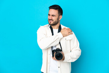 Young photographer man isolated on blue background suffering from pain in shoulder for having made an effort