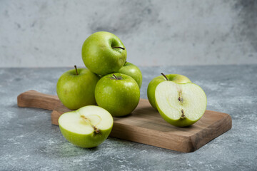 Fototapeta na wymiar Green whole and sliced apples on wooden board