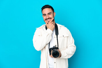 Young photographer man isolated on blue background happy and smiling