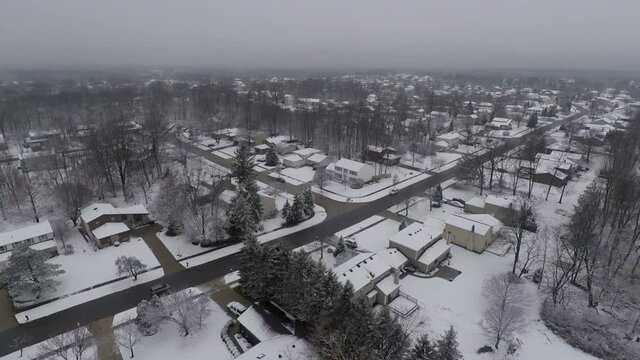 A drone flys over Strongsville, Ohio which is a suburb of Cleveland.  It's winter time in the midwestern town.  Snow covers the once lush grass. 