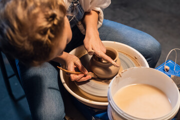 the process of modeling a clay vase shows a young potter in his Studio
