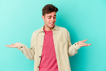 Young caucasian man isolated on blue background holding something with palms, offering to camera.