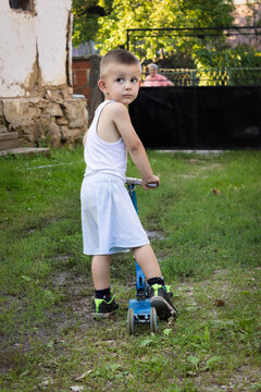 Outdoor Photo Of A Boy On A Scooter In His Backyard