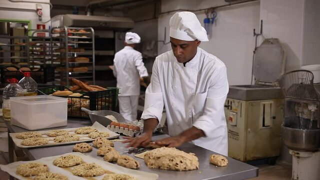 portrait of latino male baker making cookies in bakehouse