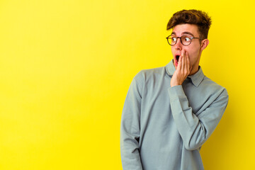 Young caucasian man isolated on yellow background being shocked because of something she has seen.