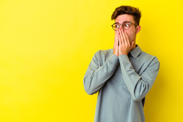 Young caucasian man isolated on yellow background thoughtful looking to a copy space covering mouth with hand.