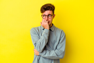 Obraz premium Young caucasian man isolated on yellow background biting fingernails, nervous and very anxious.