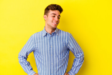 Young caucasian man isolated on yellow background confident keeping hands on hips.