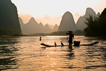 Silhouette of cormorant fisherman on the Li River (Lijiang) with karst peaks in the background at...