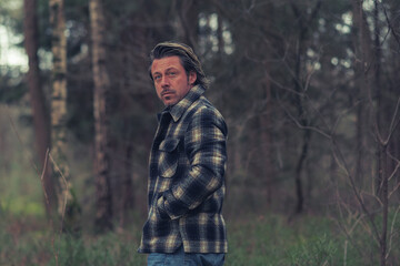 Cool man in checkered coat in the woods.