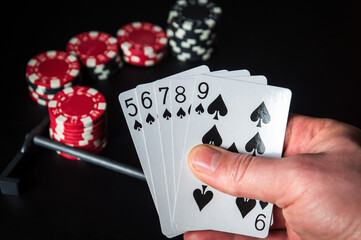 Poker cards with straight flush combination. Close up of a gambler hand is holding playing cards in casino