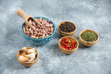 Bowl of raw beans and spices on marble background