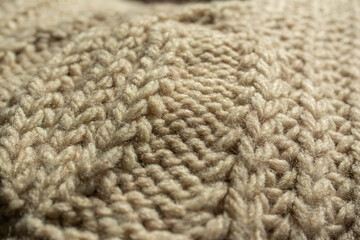 Close-up of the central twist of a large knitted jumper. Beige, natural colour.