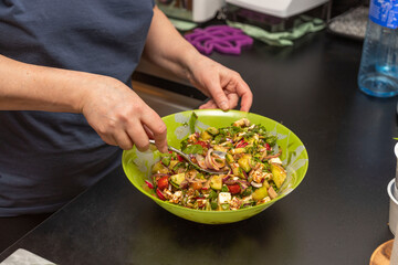 Close up view of woman making healthy green salad bowl. 