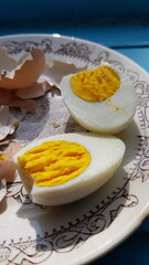 Closeup hard boiled egg sliced in halves and broken eggshell on retro crockery plate. Organic farm chicken egg cooked for breakfast. Healthy eating nutrition