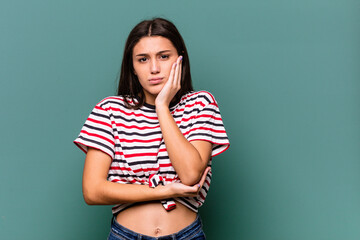 Young Indian woman isolated on blue background blows cheeks, has tired expression. Facial...
