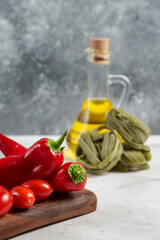 Green tagliatelle, vegetables and olive oil on marble background