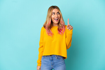 Young woman over isolated blue background intending to realizes the solution while lifting a finger up