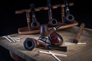 Smoking pipes of different shapes and types in a special rack.