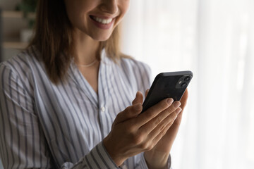 Close up smiling woman holding phone, typing on screen, writing message or surfing internet, happy young female using smartphone, having fun with gadget, browsing apps, enjoying leisure time