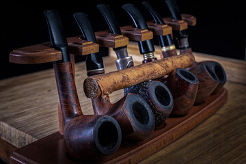 Smoking pipes of different shapes and types in a special rack.