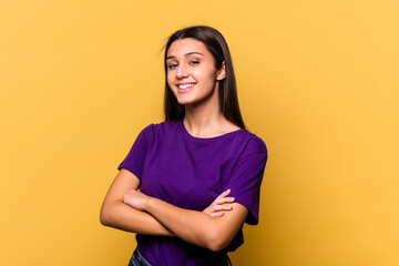 Obraz premium Young Indian woman isolated on yellow background who feels confident, crossing arms with determination.