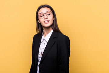 Young Indian business woman isolated on yellow background looks aside smiling, cheerful and pleasant.