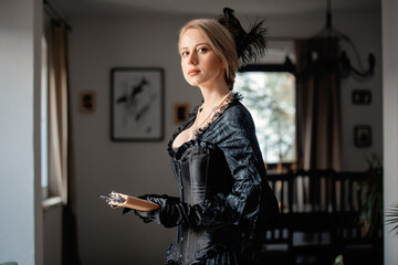 Fototapeta na wymiar Beautiful woman in black dress holding a book and lavender flowers indoor