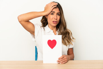 Young caucasian woman holding a valentines day card isolated being shocked, she has remembered important meeting.