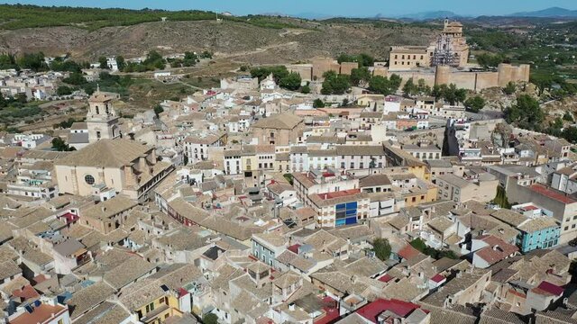 Aerial view of fortified castle and Basilica of Vera Cruz on hill dominating residential areas of Spanish town of Caravaca de la Cruz on summer day. High quality 4k footage