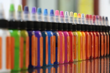 Tintas de colores en envases de plástico formadas en una fila y fondo bokeh