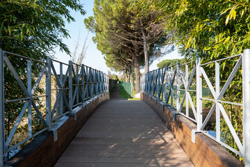 wooden bridge with iron railing across the river in an empty park, no people