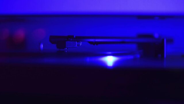 A record player playing a record while a colorful light flashes, close up.