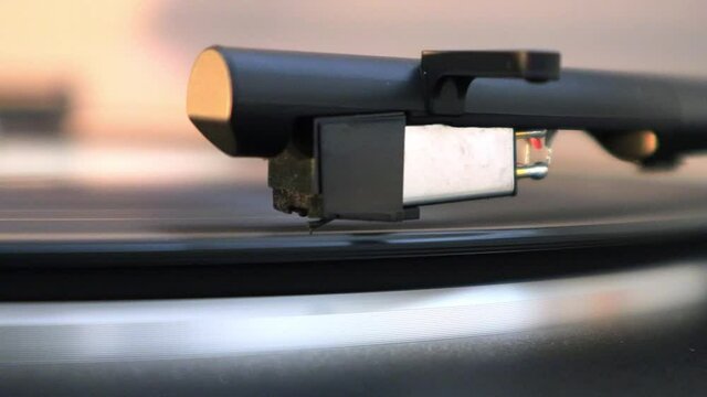 A record arms sits on vinyl playing a song, close up.