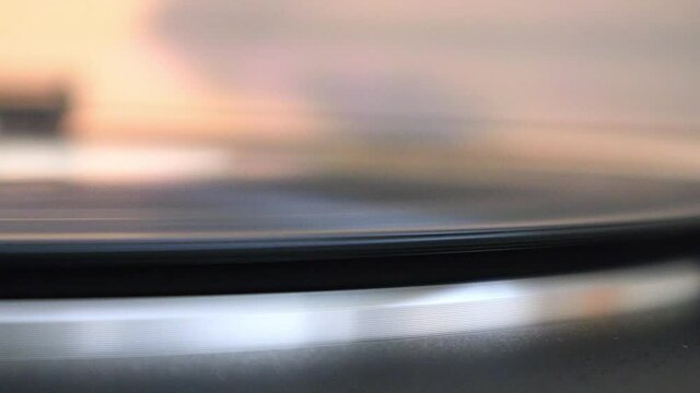 A record begins to spin on a record player, and the record arm sits on the vinyl, close up.