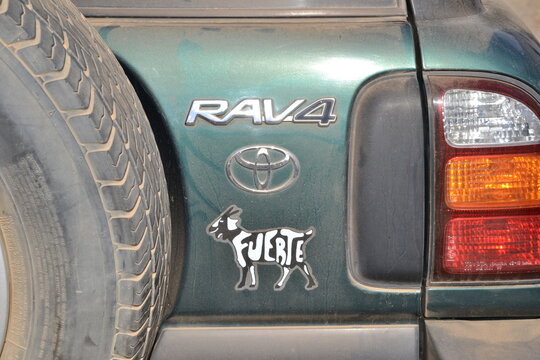 Dirty, dusty part of the back of the Toyota RAV4 from a local rental company with a goat sticker (symbol of the island of Fuerteventura) and Fuerte text. Fuerteventura, Spain - January 8 2013