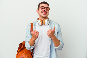Young caucasian student man listening to music isolated on white background raising both thumbs up,...