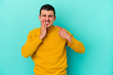 Young caucasian man isolated on blue background having a strong teeth pain, molar ache.