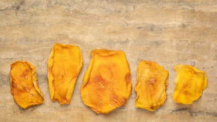 slices of dried mango fruit against textured bark paper with a copy space